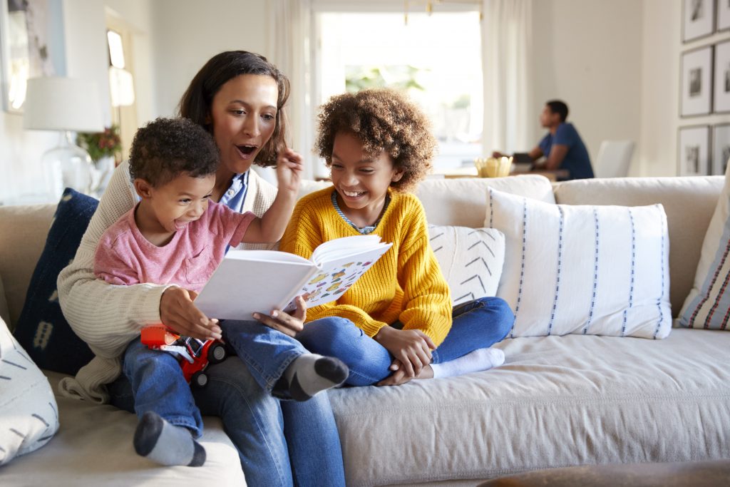 Woman sitting on the couch reading to two children 